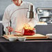 An Avantco carving station with a chef slicing a piece of meat on a cutting board.