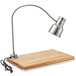 An Avantco stainless steel carving station lamp on a wooden cutting board.