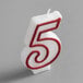 A white birthday candle with red outlined number 5.