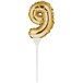 A gold foil balloon shaped like the number 9 on a white stick.