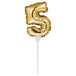 A gold foil balloon in the shape of the number 5 on a white stick.
