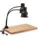 An Avantco black dual arm heat lamp on a wooden cutting board.