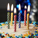 Assorted primary color spiral candles on a birthday cake.
