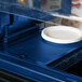 A navy blue Cambro Versa well cover on a blue surface with a white plate inside.