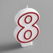 A white candle with red outlined number "8" in the middle.