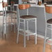 A group of Lancaster Table & Seating bar stools with dark brown vinyl seats and antique walnut backs.