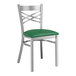 A Lancaster Table & Seating clear coat finish cross back chair with a green vinyl padded seat.