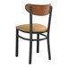 A Lancaster Table & Seating Boomerang Series black wood chair with light brown vinyl seat.