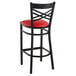 A Lancaster Table & Seating black cross back bar stool with a red padded seat.