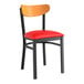 A black Lancaster Table & Seating chair with a red vinyl cushion and cherry wood back.