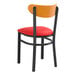 A Lancaster Table & Seating Boomerang Series black chair with red vinyl seat and cherry wood back.