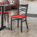 A Lancaster Table & Seating black cross back chair with a red vinyl padded seat.