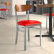 A Lancaster Table & Seating Boomerang chair with a red vinyl seat and wood back on a table in a restaurant.