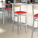 Lancaster Table & Seating Boomerang bar stools with red vinyl seats and driftwood backs at a restaurant counter.