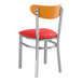 A Lancaster Table & Seating Boomerang chair with a red vinyl cushion and cherry wood back on a metal frame.