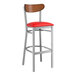 A Lancaster Table & Seating bar stool with a red vinyl seat and wooden back.