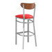 A Lancaster Table & Seating bar stool with a red vinyl seat and wood back with a clear coat finish.