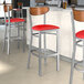 Lancaster Table & Seating bar stools with red vinyl seats and walnut backs at a restaurant counter.
