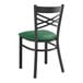 A black Lancaster Table & Seating cross back chair with a green vinyl padded seat.