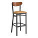 A Lancaster Table & Seating black bar stool with a brown cushion and wooden back.