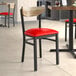A Lancaster Table & Seating Boomerang Series chair with a red vinyl seat and driftwood back.