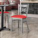 A Lancaster Table & Seating clear coat finish cross back chair with a red vinyl padded seat at a table in a restaurant.