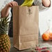 A person putting bananas in a Duro brown paper bag.