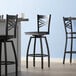 A Lancaster Table & Seating black swivel bar stool with a black wood seat.