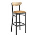 A Lancaster Table & Seating black bar stool with a light brown wooden seat and driftwood back.