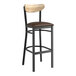 A Lancaster Table & Seating black bar stool with a dark brown vinyl seat and driftwood back.