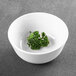 A white Elite Global Solutions melamine bowl with green leaves in it.