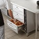 A man using the ServIt triple freestanding drawer warmer to put food in a drawer.