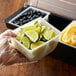 A Tablecraft white condiment dispenser insert in a bowl of lime and lemon wedges.