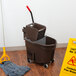 A Rubbermaid WaveBrake mop bucket with a mop and caution sign on the floor.