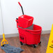 A Rubbermaid red mop bucket with a gray dirty water bucket and black handles.