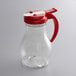 A clear polycarbonate teardrop syrup server with a red lid.