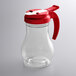 A clear polycarbonate teardrop syrup server with a red lid.