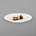 A RAK Porcelain ivory flat plate with a cookie, a group of cookies, and a dessert on it.