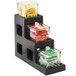 A black Cal-Mil three tier jar display with different types of condiments in it.