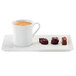 A RAK Porcelain ivory coffee cup filled with coffee on a white plate with chocolate candies.