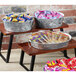 Two oval galvanized metal trays filled with candy bars on a table in a bakery display.