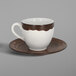 A white and brown Woodart porcelain coffee cup and saucer on a table.