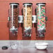A Zevro SmartSpace triple dry food dispenser on a hotel buffet counter filled with cereal and other dry foods.