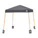 A grey E-Z Up instant shelter with orange weight bags on the legs.