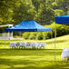 A blue Backyard Pro canopy set up in a grassy area with tables and chairs and a white tablecloth.