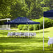 A navy blue Backyard Pro instant canopy set up in a grassy area with tables and chairs.