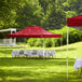 A red Backyard Pro canopy set up in a field with tables and chairs.