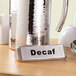 An American Metalcraft stainless steel table tent with "Decaf" on a table.