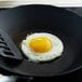 A fried egg in a Lodge yellow silicone egg ring in a frying pan.
