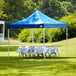 A blue Galaxy Equipment canopy set up with a table and white tablecloth on grass.